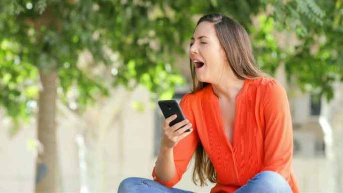 女人用智能手机打哈欠