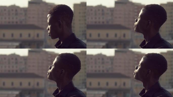 年轻的非洲黑人男子抬起头，在背景中寻找太阳城