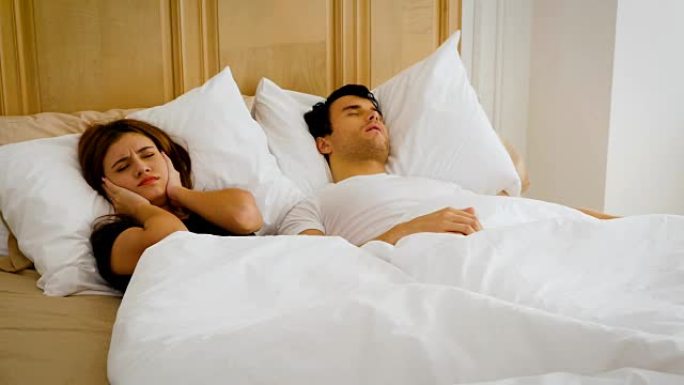 年轻夫妇在家里，人，家人和就寝时间概念上对男人在床上打鼾有问题