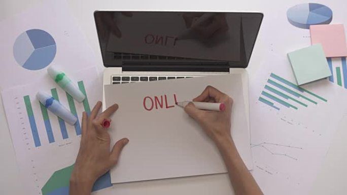 女人在笔记本电脑上的纸上写在线工作。带图表的办公桌面