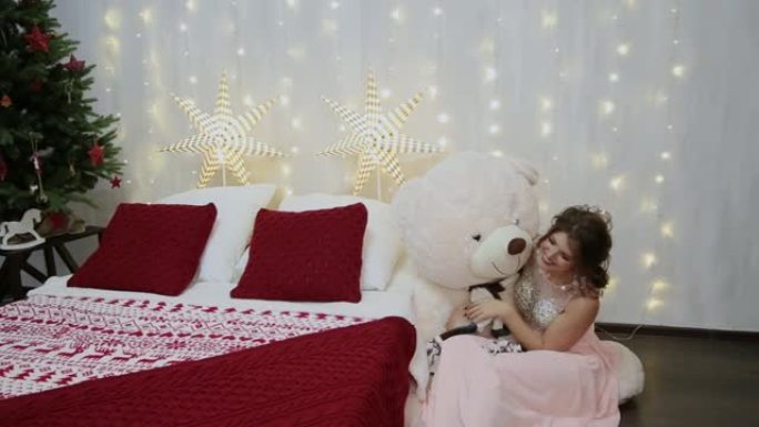 非常漂亮的女孩在圣诞床上抱着一只大熊