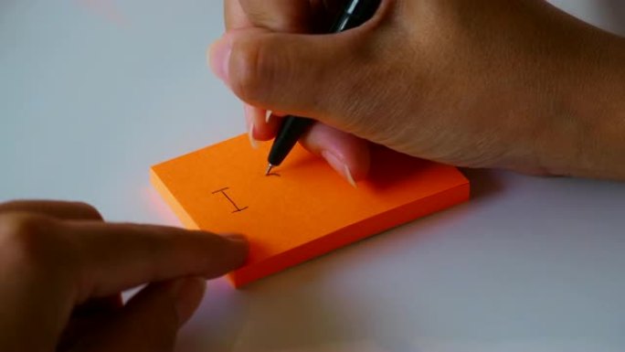 在橙色的便签纸或记事本上手写 “我爱你” 一词
