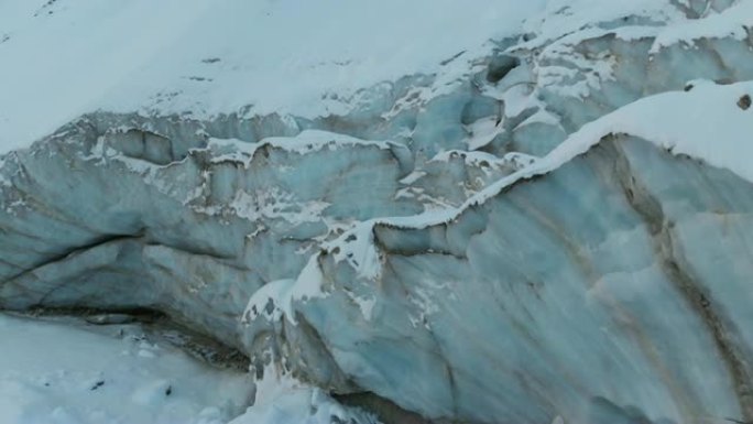 鸟瞰图特写边缘流动的冰川覆盖着高山上的雪和石头。冰川融化的自然破坏和全球变暖