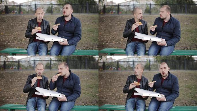 两个男人在公园长椅上吃盒子里的外卖披萨