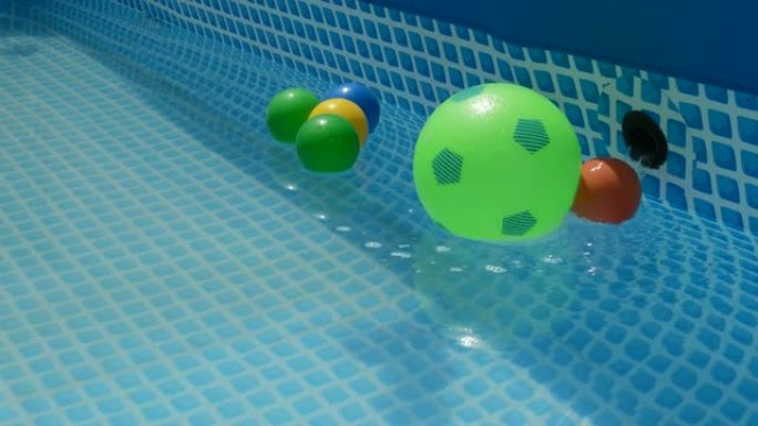 彩球漂浮在一个小的夏季游泳池的水中
