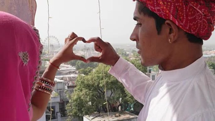 印度拉贾斯坦邦，一对拉贾斯坦邦夫妇在监督普什卡尔梅拉节，他们用手做心形手势