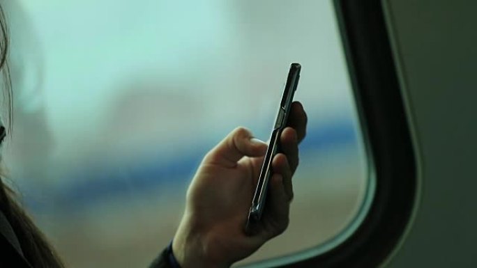 手持智能手机设备的特写镜头，背景模糊。乘火车通勤时上网和查看电子邮件的人