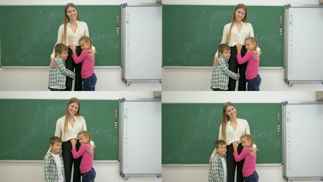 微笑的教室老师在黑板附近拥抱学习者的肖像