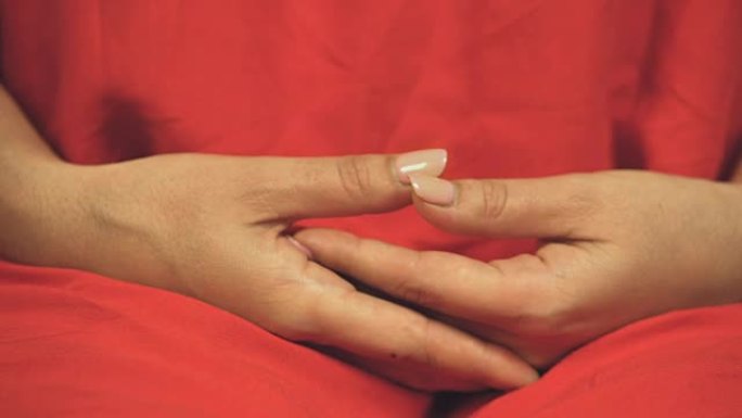 穿着彩色红色长袍的女佛教徒准备冥想，双手交叉
