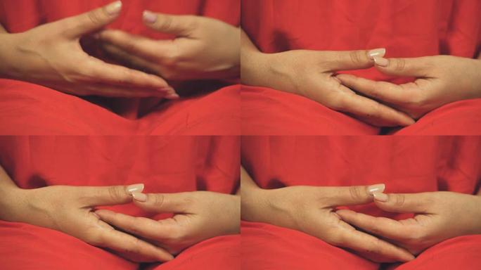 穿着彩色红色长袍的女佛教徒准备冥想，双手交叉