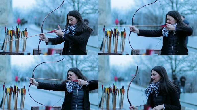 女子弓箭手用4k弓射击。练习射箭的旅游女子对着镜头微笑。女人专注于用箭击中目标。