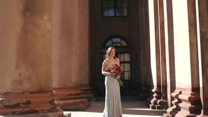 一位穿着长裙，捧着一束鲜花的女人站在柱子旁。