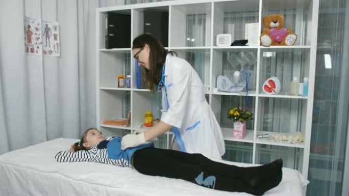 医生在医疗办公室触诊了一名年轻患者的腹部。