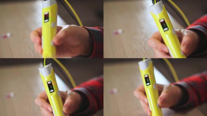 十几岁的男孩在3D笔中插入一块黄色的ABS塑料。他创造了一个塑料3D图形。