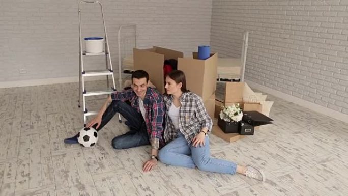 一对幸福的年轻夫妇在新公寓里用足球的肖像。