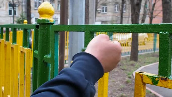 工人用绿色油漆刷油漆由黄色和绿色杆制成的金属围栏