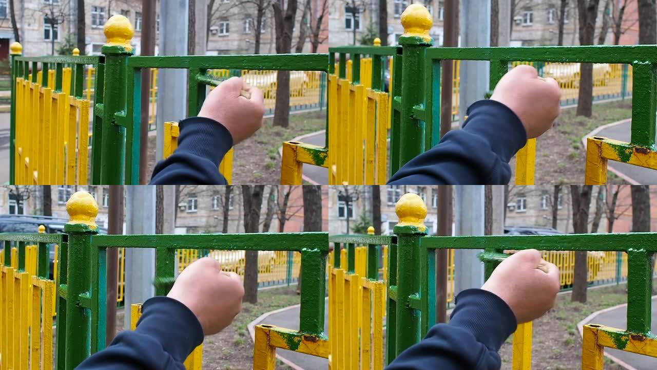 工人用绿色油漆刷油漆由黄色和绿色杆制成的金属围栏