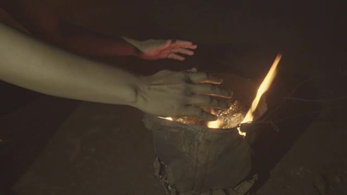在寒冷的冬夜里，赤手空拳坐在篝火前热身