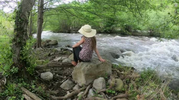 戴着帽子的年轻女子坐在河边。法国