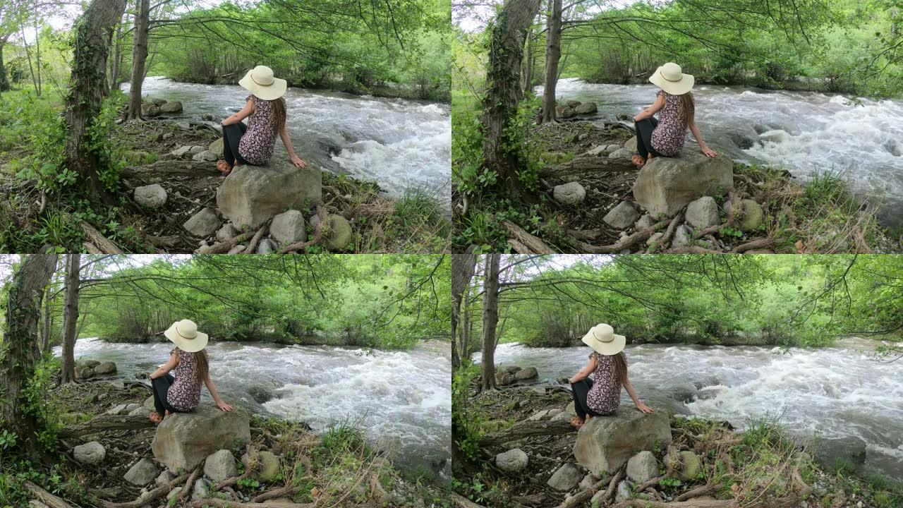 戴着帽子的年轻女子坐在河边。法国