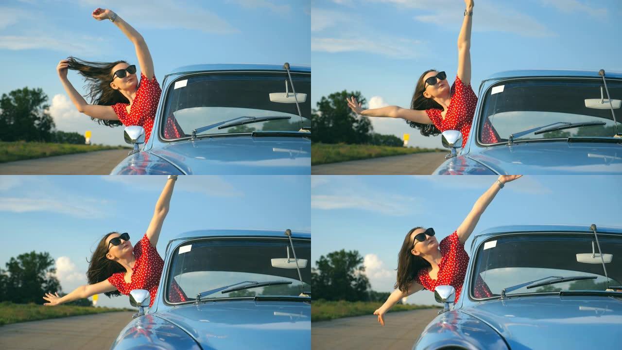 戴着太阳镜的年轻女孩斜靠在老式车窗外，享受旅行。女人从移动的复古车辆中望去。旅行和自由概念。背景模糊