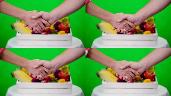 在工作室里，特写镜头，在Chromakey上友好握手，绿色背景和一个装满不同蔬菜的盒子。作物计数、蔬