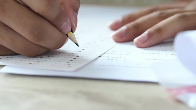 亚洲学生在学习在线学习或通过笔记本电脑进行电子学习时在笔记本上注明。女商人为木桌办公室的规划工作写作