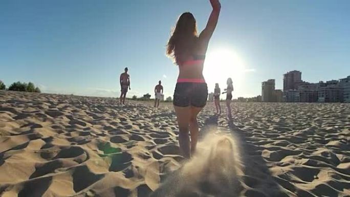 苗条的运动女孩在沙滩上奔跑，停下来并将球转移给朋友，沙滩排球