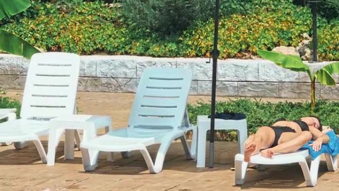女人在游泳池旁的椅子上晒日光浴