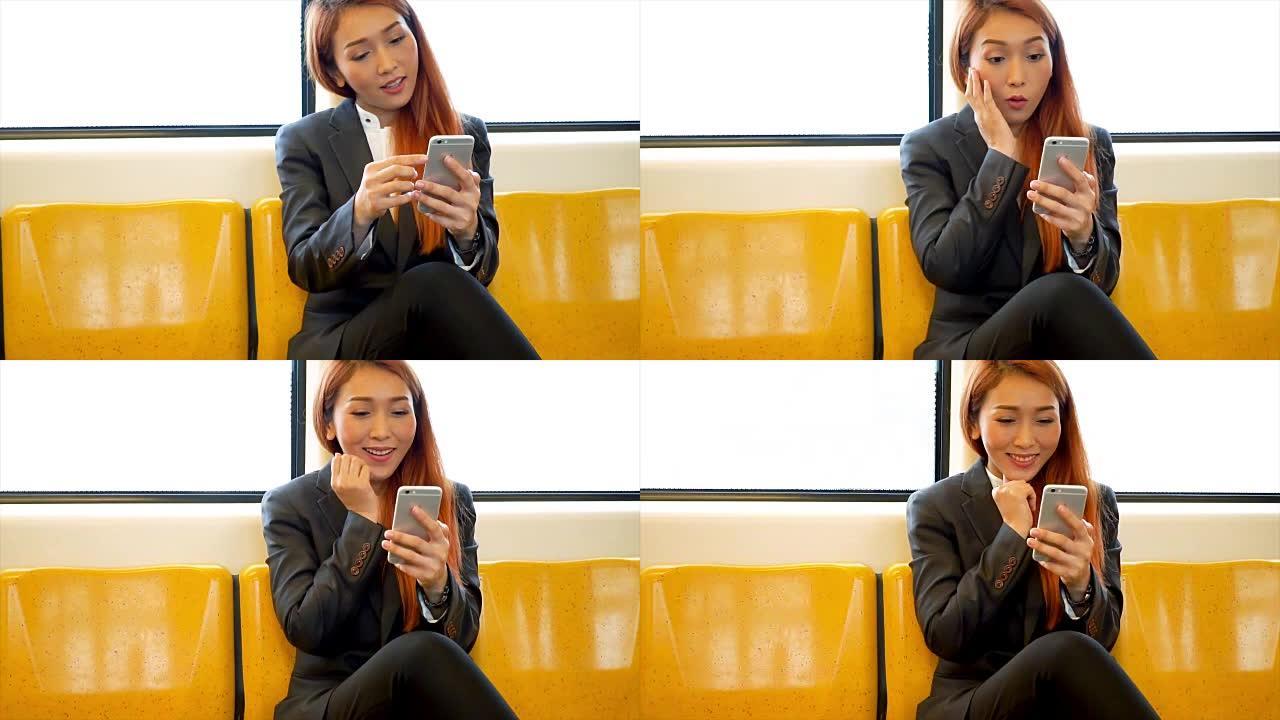 年轻的亚洲女商人使用手机并在火车内获得惊喜好消息