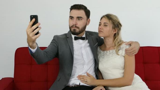 新婚夫妇快乐开朗的夫妇拍摄智能手机自拍照片并微笑