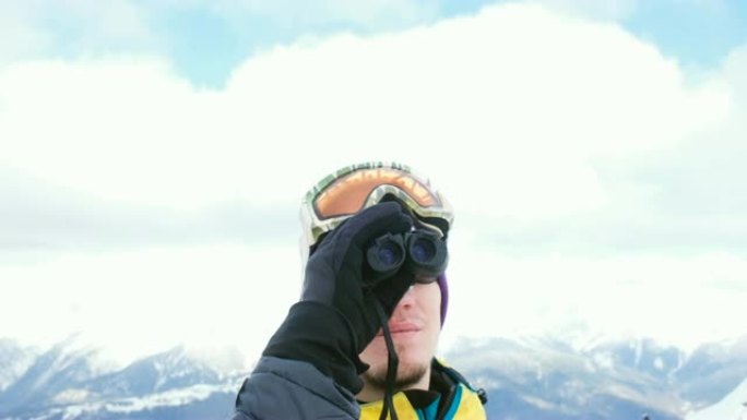 一名戴着滑雪镜的男子通过双筒望远镜望着山脉，欣赏美景，4K