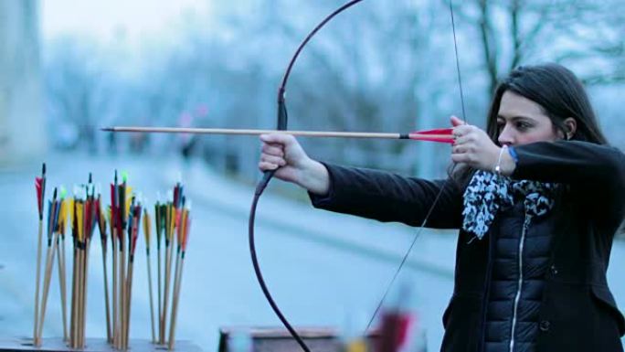 女人专注于用箭击中目标。女子弓箭手用4k弓射击。练习射箭的旅游女子。