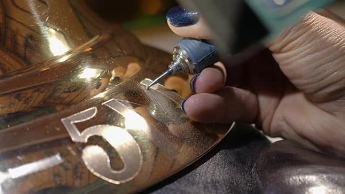 雕刻师用钻头将铭文涂在铃铛上。