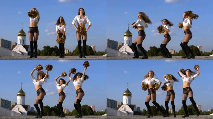 三人女孩啦啦队与绒球在户外跳舞