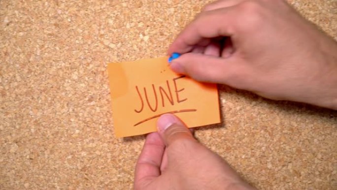 一个男人钉在软木板上的纸上6月字
