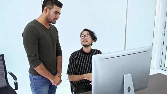 小型团队会议。亚洲男子和印度男子坐在一起争论电脑工作。多伦理商业团队创业ups概念。