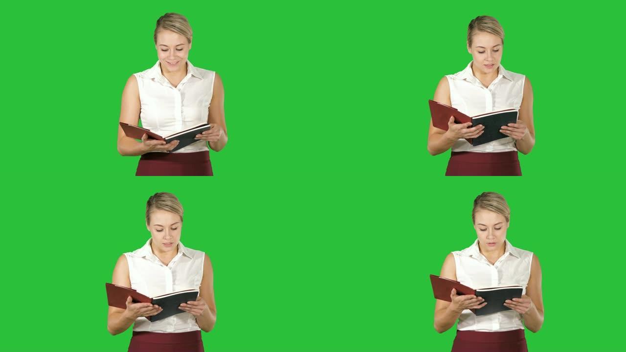 女人拿着并打开书本或笔记本，在绿色屏幕上大声朗读一些东西，色度键