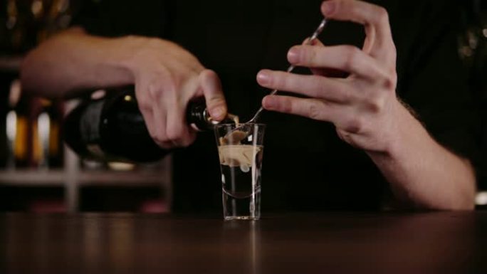 酒保在餐厅制作酒精鸡尾酒。专家酒保正在夜总会添加配料鸡尾酒