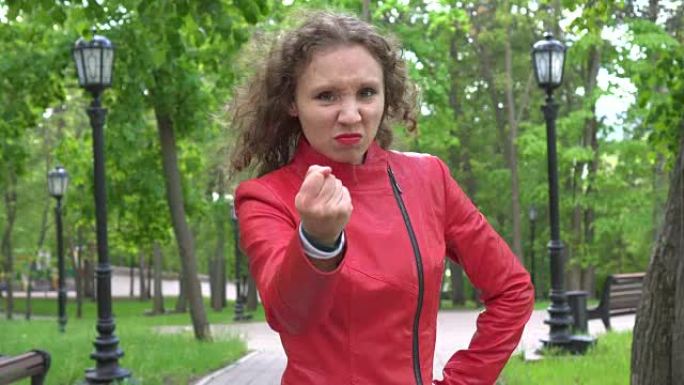 愤怒的愤怒不安愤怒的女孩在20出头时穿着红色皮夹克在空中挥舞着拳头