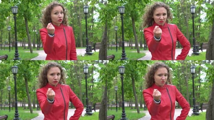 愤怒的愤怒不安愤怒的女孩在20出头时穿着红色皮夹克在空中挥舞着拳头