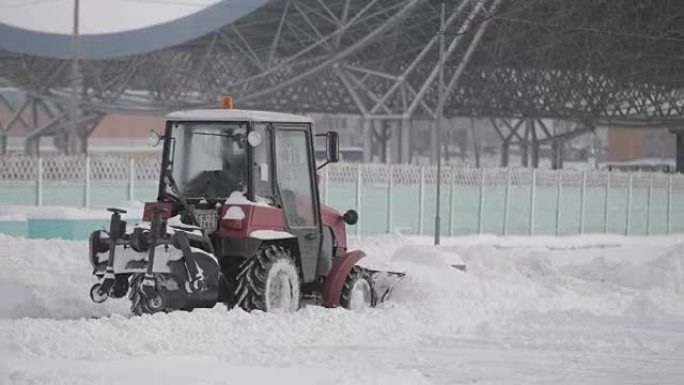 拖拉机在城市的冬天下雪。冬季服务车辆在工作。除雪车