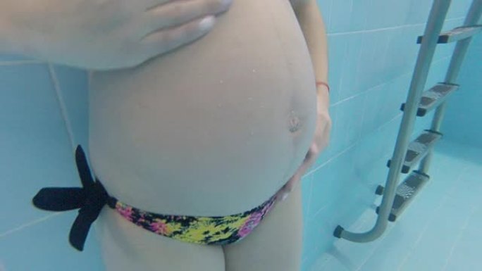 怀孕的女孩在游泳池水下游泳。