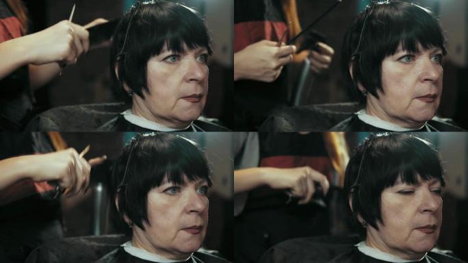 发型师在美发沙龙理发时剪掉女性头发。