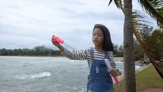 慢动作亚洲小女孩在海滩附近玩泡泡气球