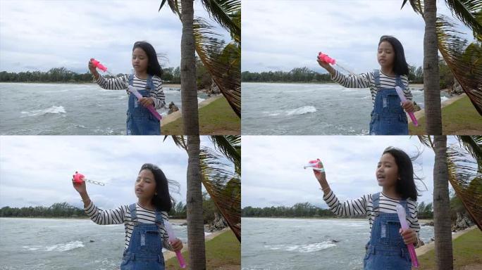 慢动作亚洲小女孩在海滩附近玩泡泡气球