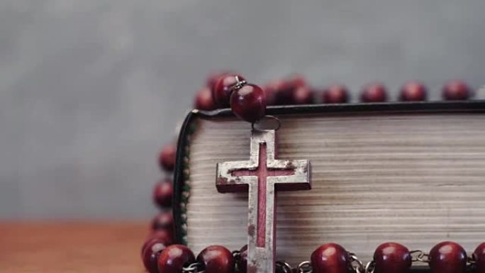 圣经和红色木桌上的耶稣受难像珠子。美丽的背景。宗教概念特写