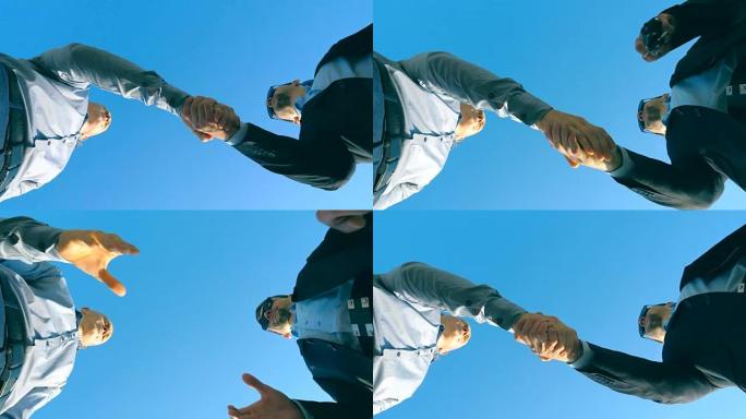 年轻的推销员穿着正式的西装与男性买家打招呼，并在蓝天背景上给他汽车钥匙。两个商人之间的握手。买卖运输