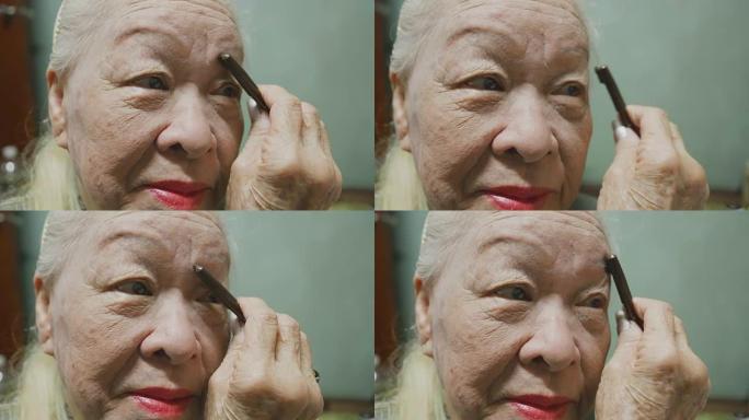 年长的女士在涂面霜、睫毛膏、口红。在家化妆。概念:美丽,生活