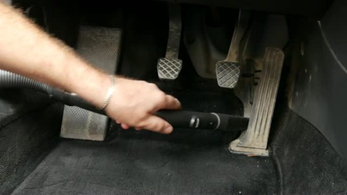 一名男子用吸尘器打扫汽车内部